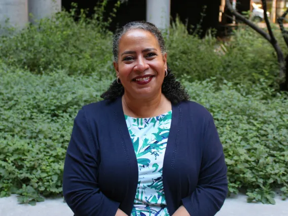 Photo of woman in front of background with plants.
